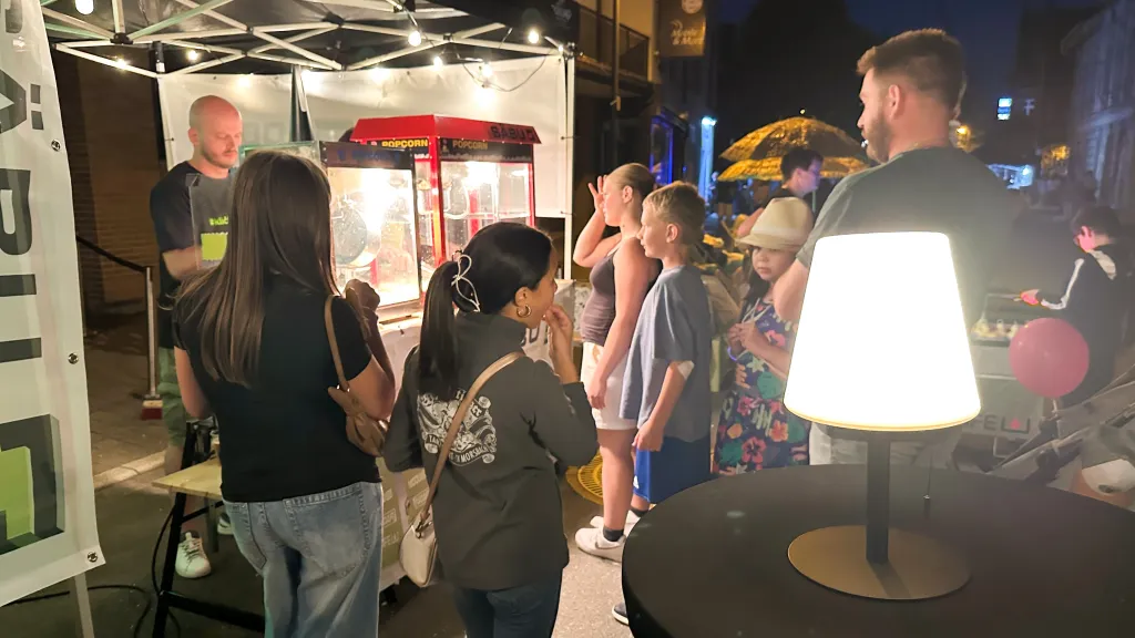 Besucher warten abends am beleuchteten Popcornstand des SÄBU-Stands bei der Langen Nacht in Morsbach.