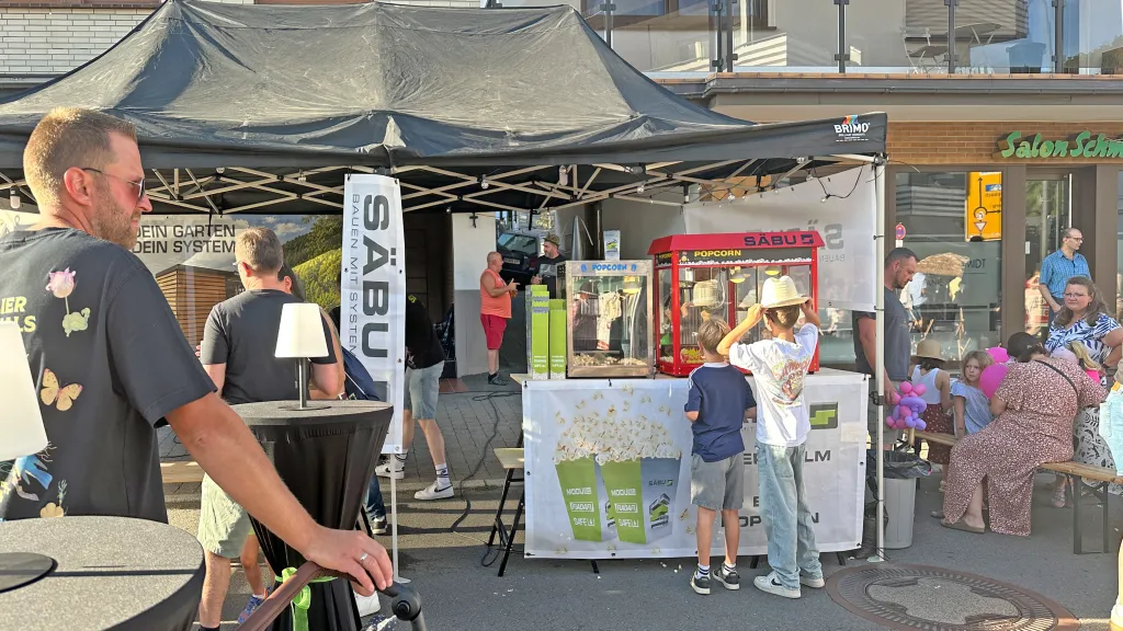 Eltern und Kinder stehen an einem Popcornstand von der Firma SÄBU.