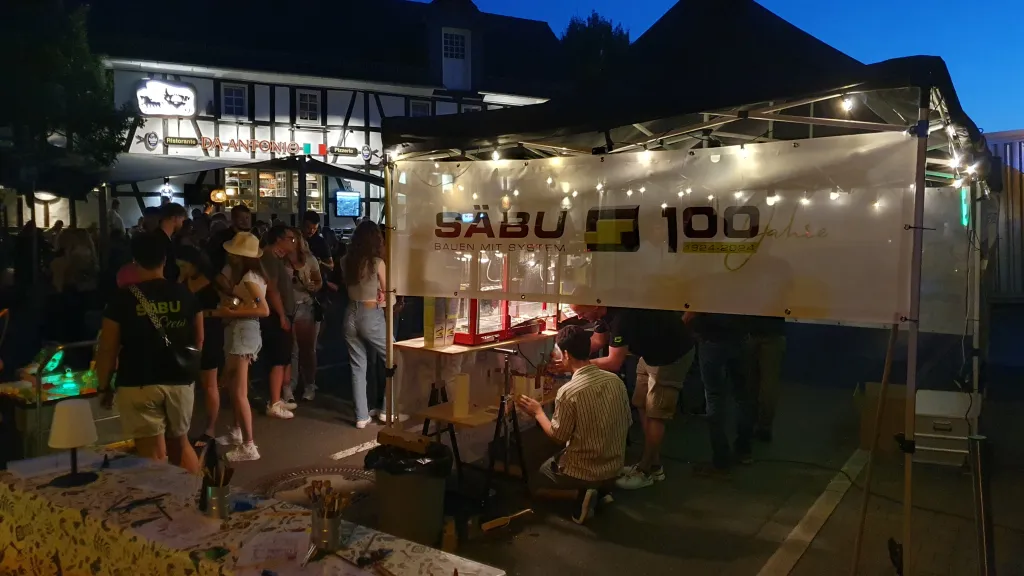 Stimmungsvoll beleuchteter SÄBU-Messestand mit Jubiläumsbanner am Abend bei der Langen Nacht in Morsbach.