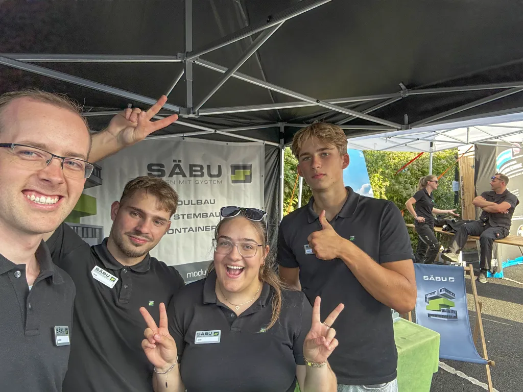 Vier gut gelaunte Teammitglieder der Firma Säbu lächeln auf der Ausbildungs- und Berufsorientierungsmesse in die Kamera.