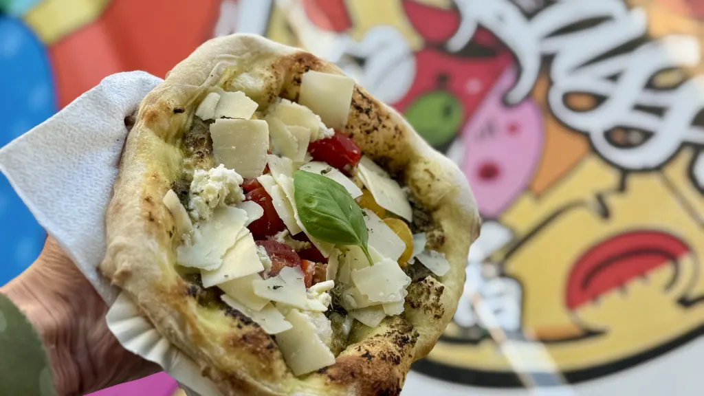 Frisch gebackene Pinsa mit Parmesankäse und Basilikum auf einer Servierte beim Familienfest.